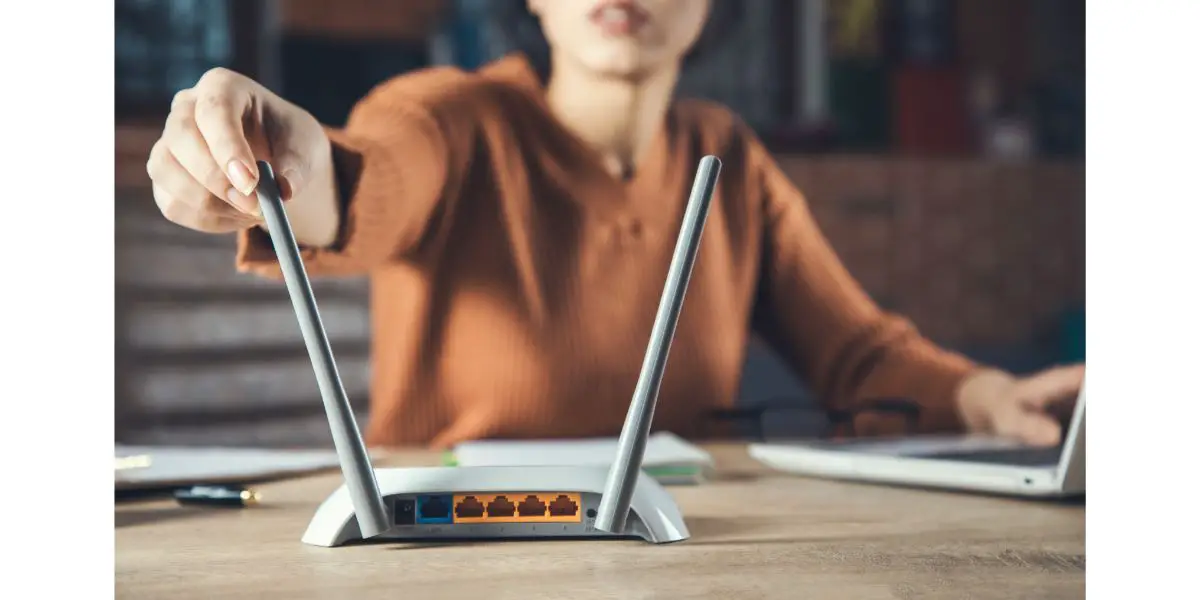 AdobeStock_336512864 woman hand touching antenna of a wireless router