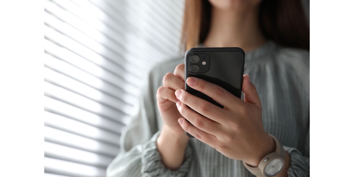 AdobeStock_338593770 Woman holding iPhone 11 Black indoors, closeup