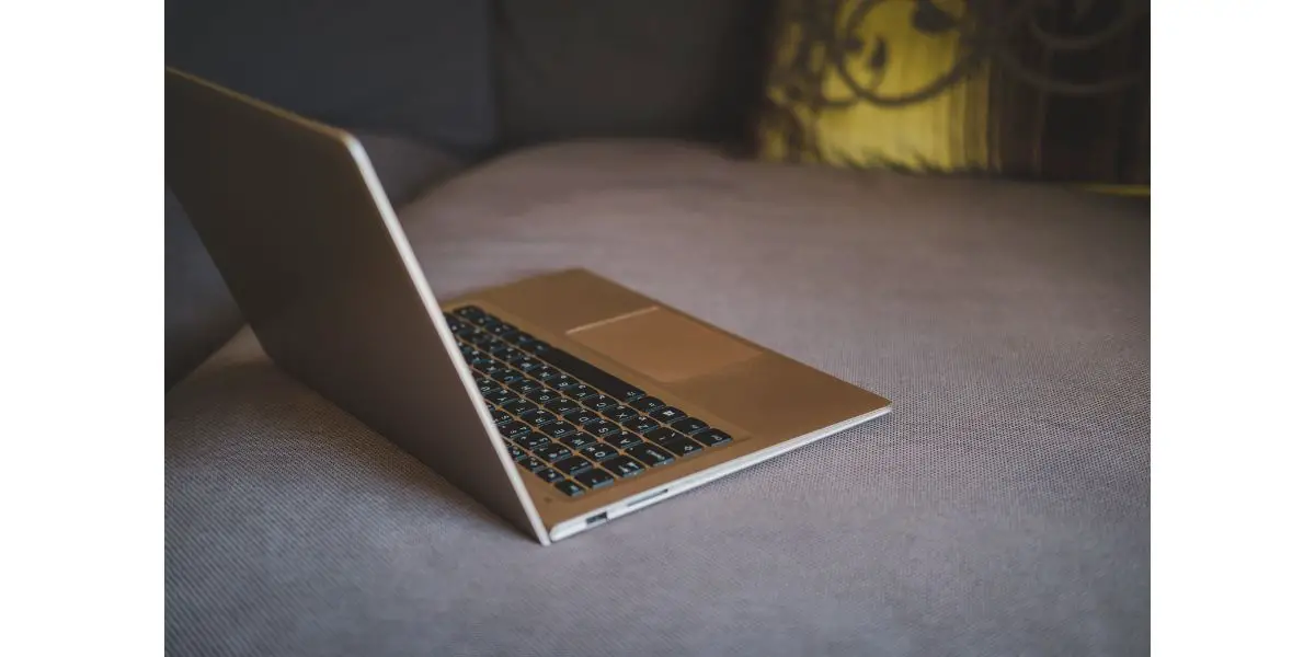 AdobeStock_339575122 white laptop tilted not to show screen on grey sofa