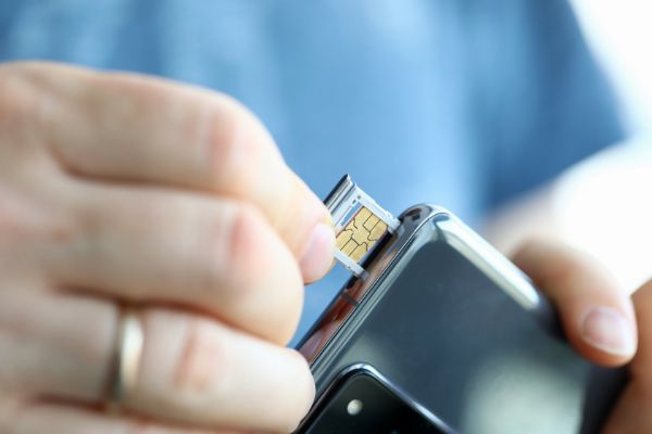 AdobeStock_341749226 Male hands getting sim card slot of his smartphone out