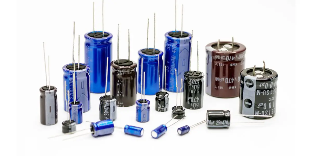 AdobeStock_347575857 Electrolytic capacitors, many colors and sizes, white background, electronic component concepts