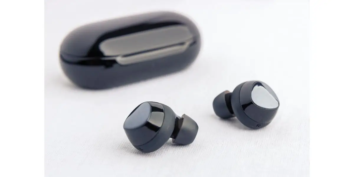 AdobeStock_350385305 galaxy Earbuds plus headphones side profile - displayed in front of opened black wireless earbud charging case