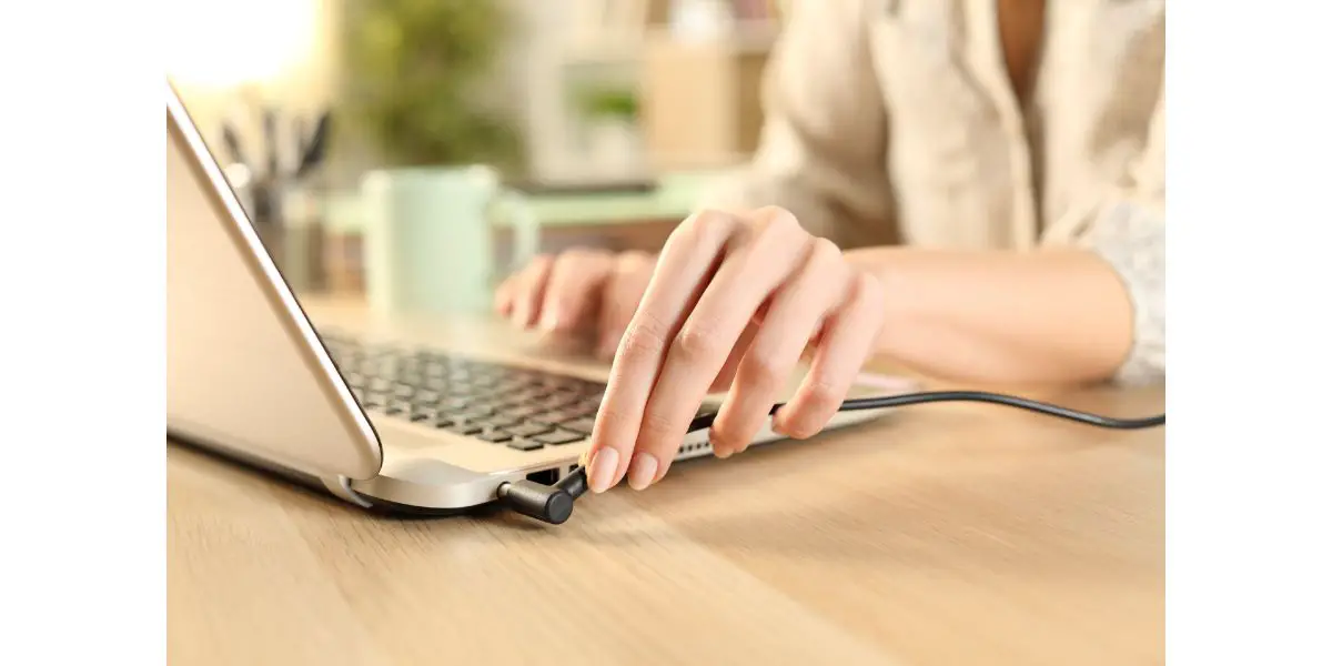 AdobeStock_352419927 Woman hands plugging battery charger on laptop