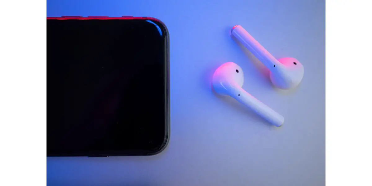 AdobeStock_354471305 Wireless headphones and side of phone on a colored background