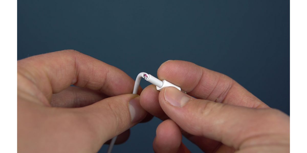 AdobeStock_354637408 Torn phone charger cable closeup. A man holds a torn wire in his hands. Wire wear