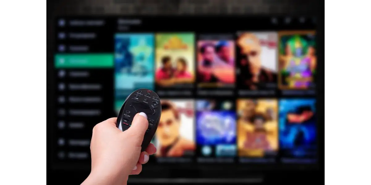 AdobeStock_354827294 Multimedia streaming concept. Hand holding remote control. TV screen with lot of pictures.