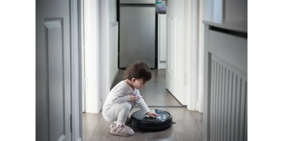 AdobeStock_373348335 Child switches on a robot vacuum in the corridor of a house in Edinburgh, Scotland, UK