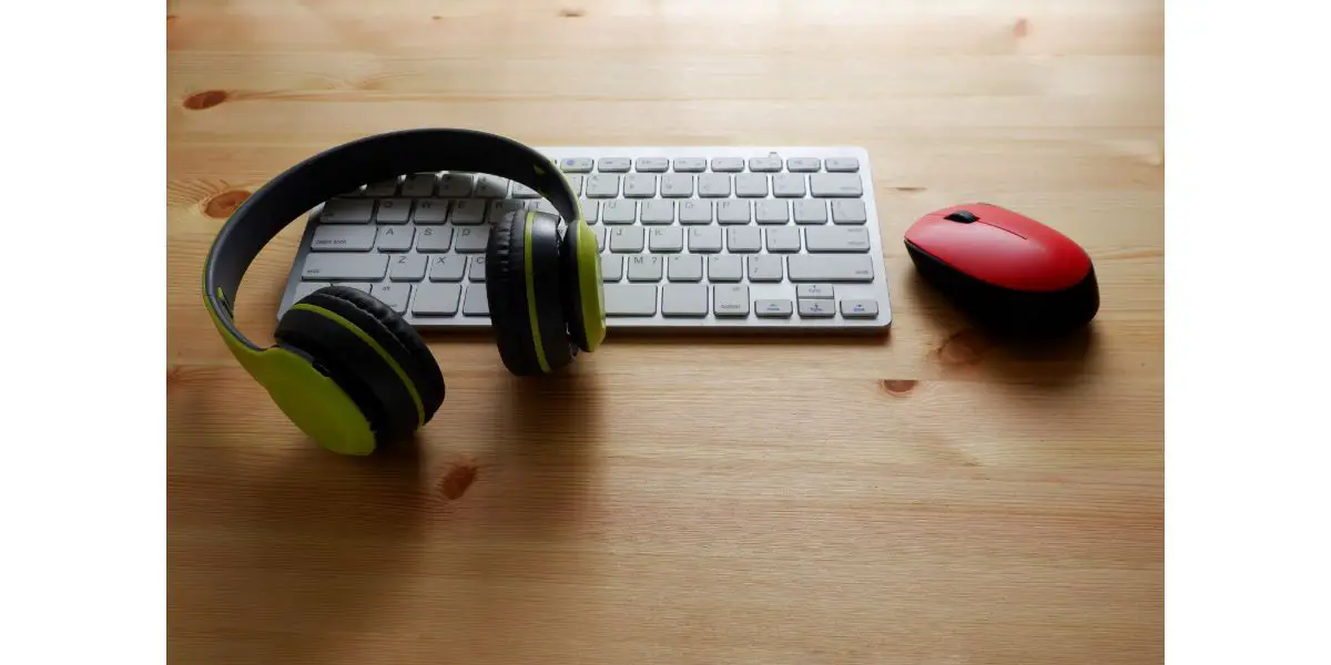 AdobeStock_383192993 White keyboard with wireless mouse and bluetooth wireless headphones on wooden background.Top view