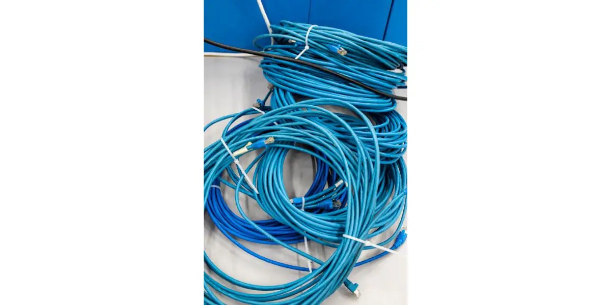 AdobeStock_388340048 Long blue network cable cord bunch set on a work bench