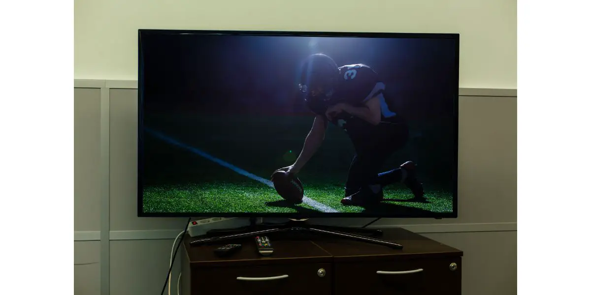 AdobeStock_391855643 Watching American football game on television bigger than drawer at home.