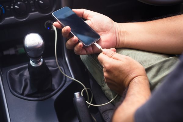 AdobeStock_398470943 Charging phone battery from power supply socket in private car