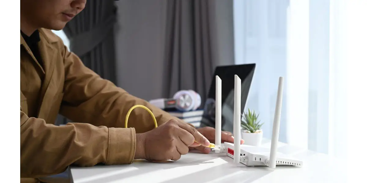 AdobeStock_406614226 Close up view of young man connects the internet cable into router wireless at home