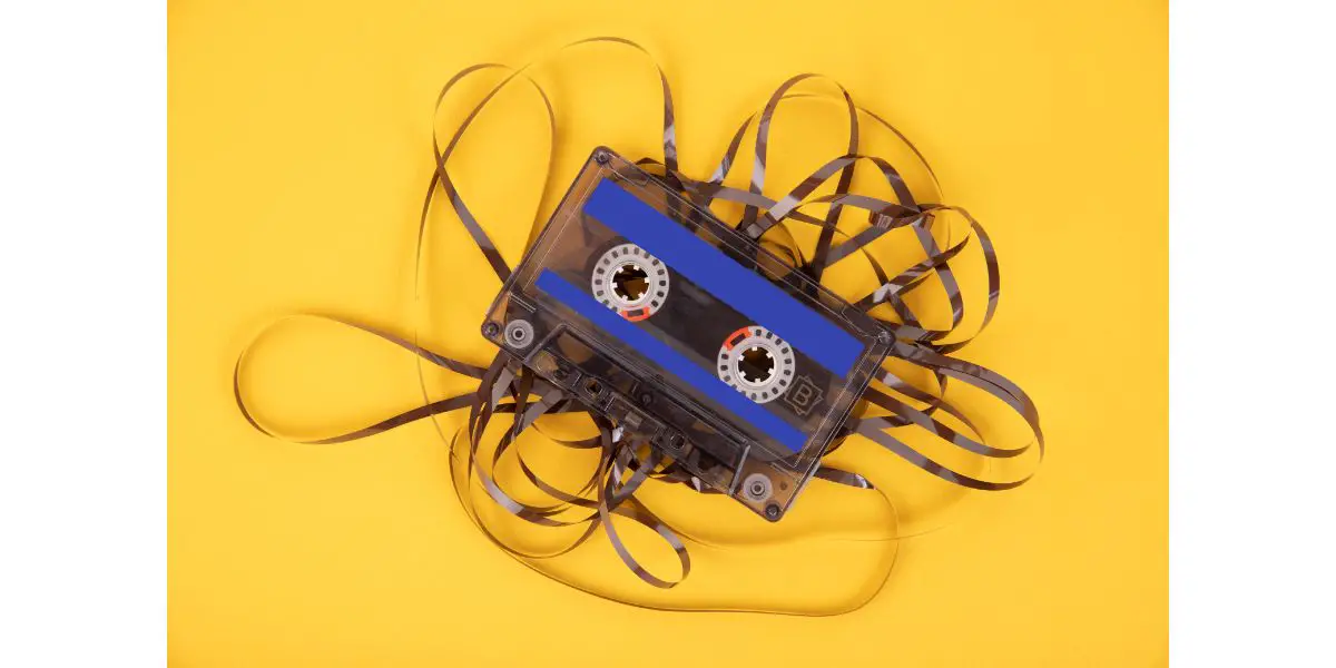 AdobeStock_410106188 Old cassette tape with unwound tape on a yellow background