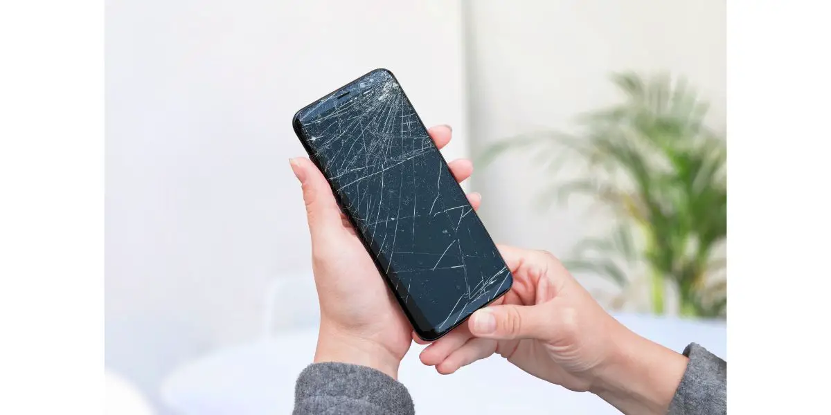 AdobeStock_411769062 Broken phone in woman hands. Smashed display concept