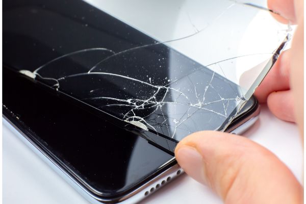 AdobeStock_413759698 Man replacing the broken tempered glass screen protector for smartphone. Close up.