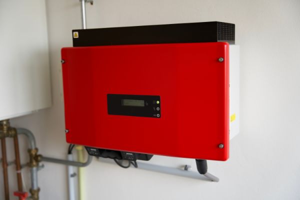 AdobeStock_415766416 red solar power inverter mounted on a white wall