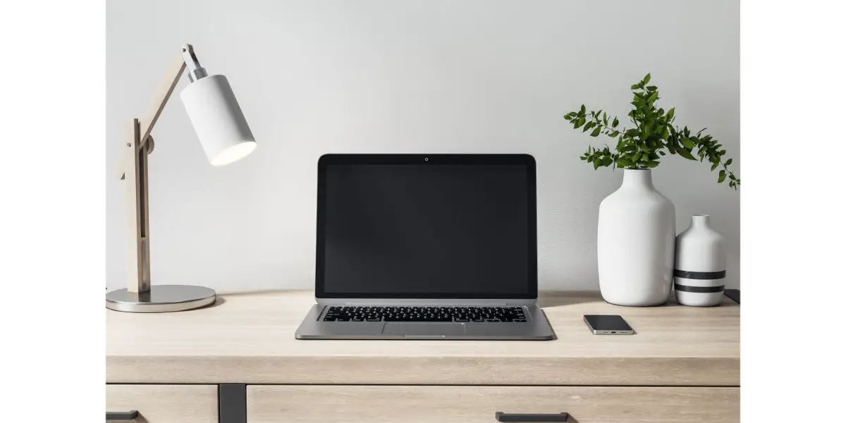 AdobeStock_416057449 Blank black laptop monitor on wooden table with decor elements for comfortable remote work.