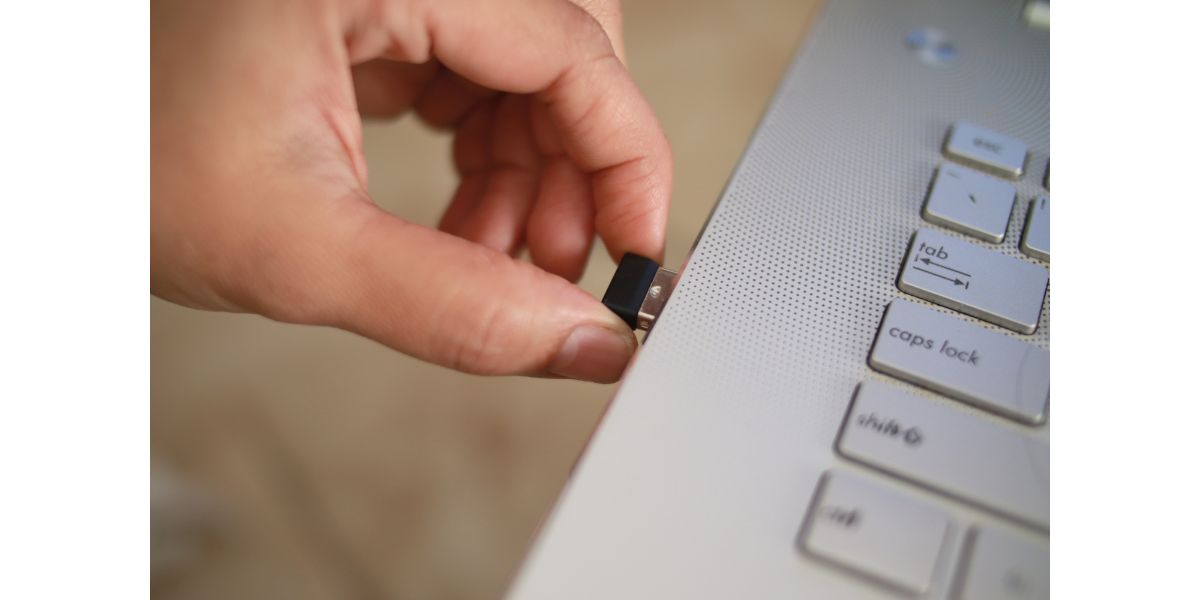 AdobeStock_420355686 Person inserting plug in wireless bluetooth mouse or wifi dongle into usb port in laptop personal computer