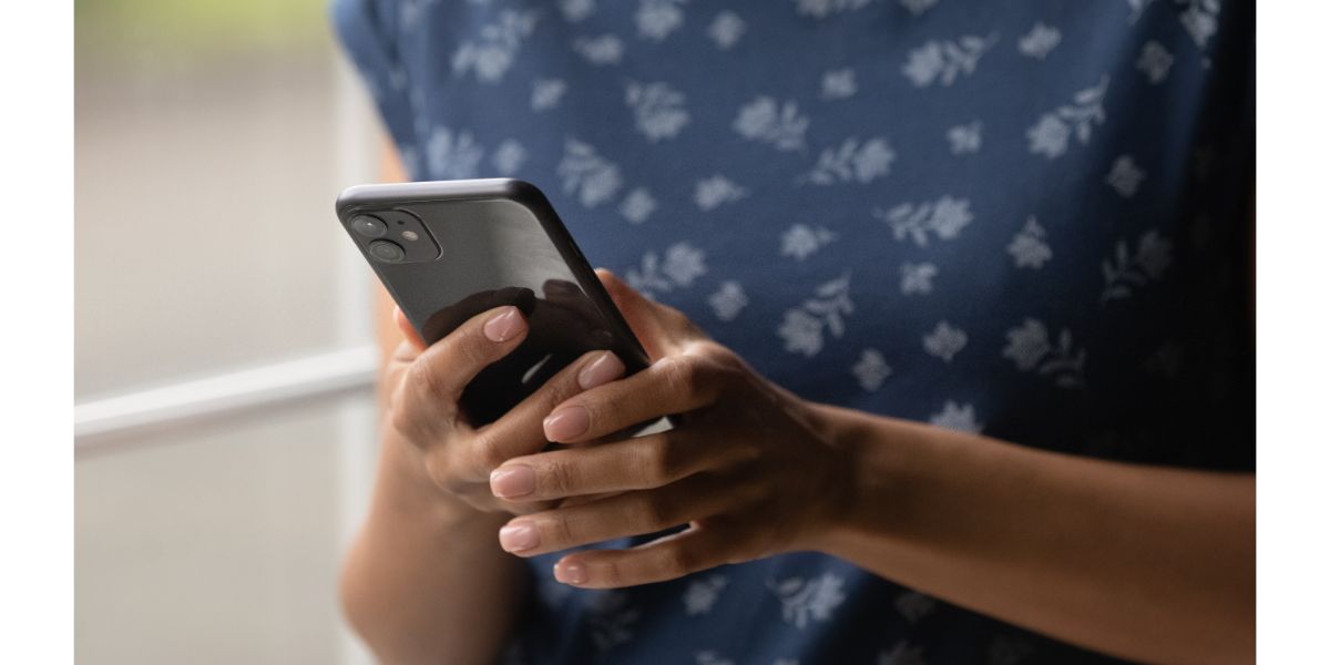 AdobeStock_420510314 Close up view of modern mobile phone device in hands of young african american female user