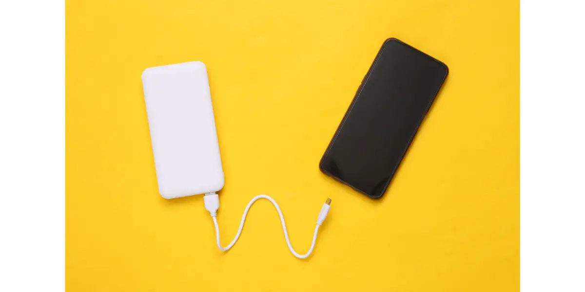 AdobeStock_431422181 Smartphone and External portable battery (power bank) on yellow background
