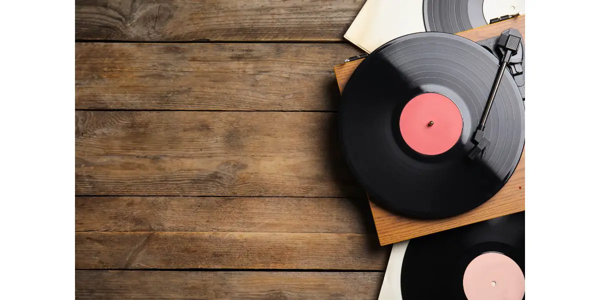 AdobeStock_433005258 Modern player and vinyl records on wooden background