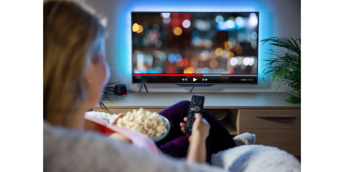 AdobeStock_435606616 Woman relaxing at home in evening and watching TV