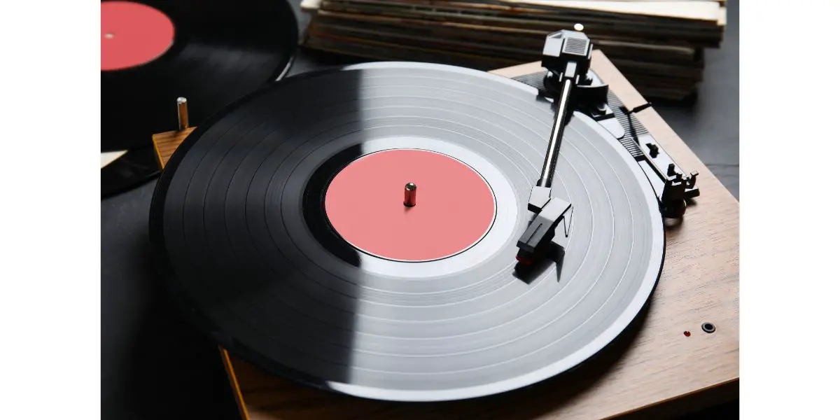 AdobeStock_442470768 Modern vinyl record player with disc on black background, closeup