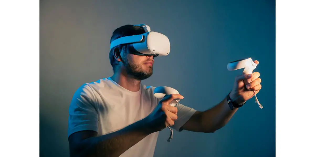 AdobeStock_443086713 young man in a white t shirt wearing Virtual Reality VR Headset. VR for gaming. Grey blue background