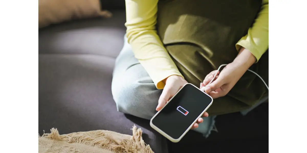 AdobeStock_454666120 Woman hands Charging mobile phone battery with low battery