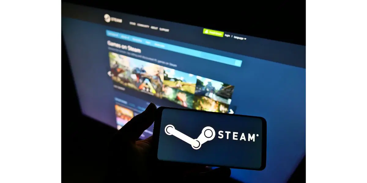 AdobeStock_456750116_Editorial_Use_Only Person holding smartphone with logo of Steam operated by Valve on screen in front of website.