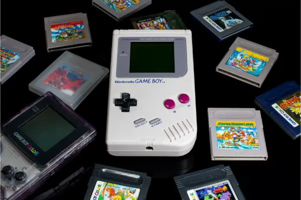 AdobeStock_457788551_Editorial_Use_Only nintendo game boy and game boy color with various game cartridges isolated on black background