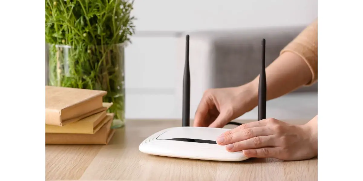 AdobeStock_464942111 Woman inserting ethernet wire into wi-fi router on table in room