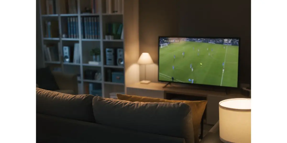 AdobeStock_469272229 Football match live on TV in cozy living room with a bookshelf