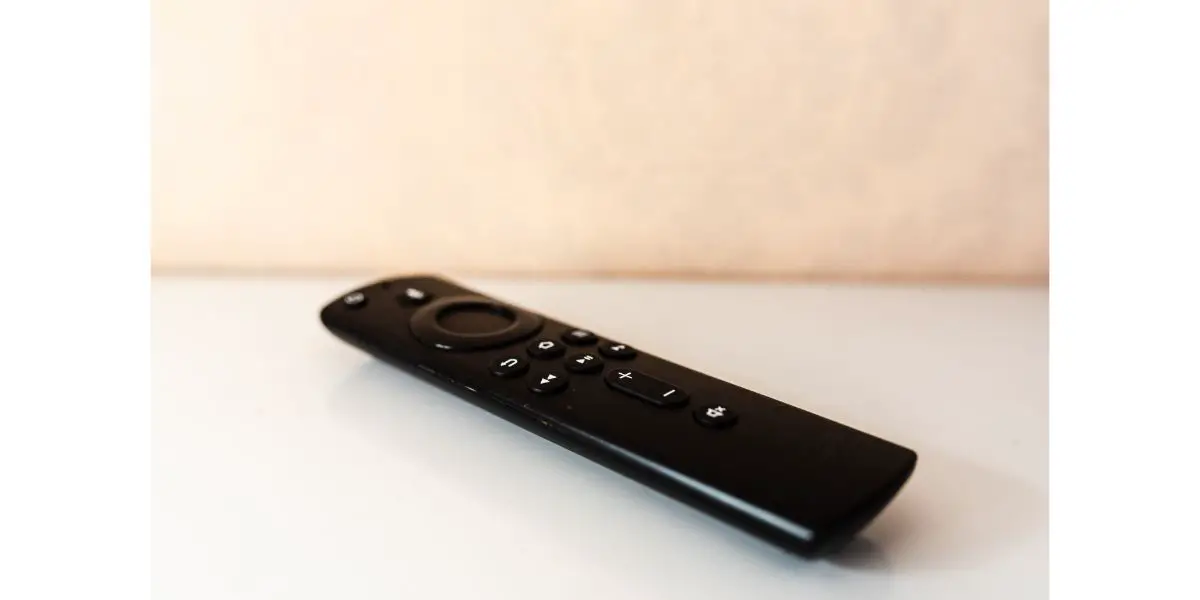 AdobeStock_510684285 amazon fire tv stick remote control on white surface and beige background.