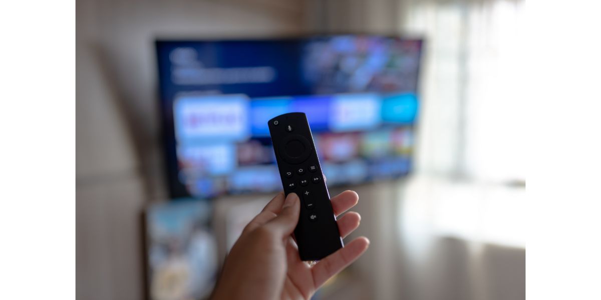 AdobeStock_510684288 amazon fire tv stick remote in hand with selective focus tv background