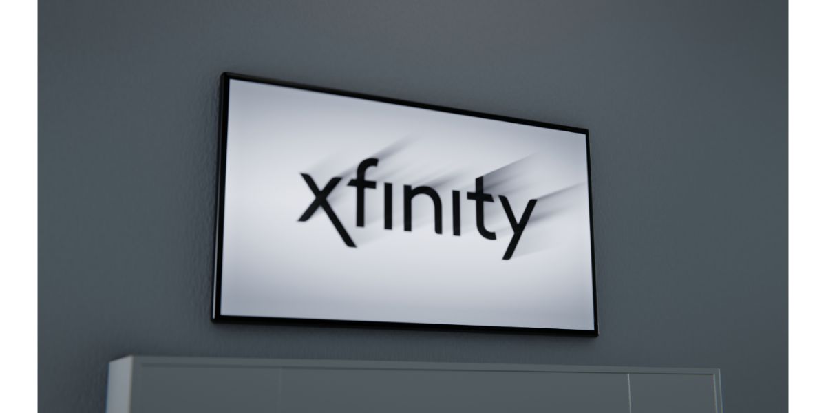 AdobeStock_516966330_Editorial_Use_Only Xfinity logo displayed on flatscreen TV floating above white tv stand on grey background