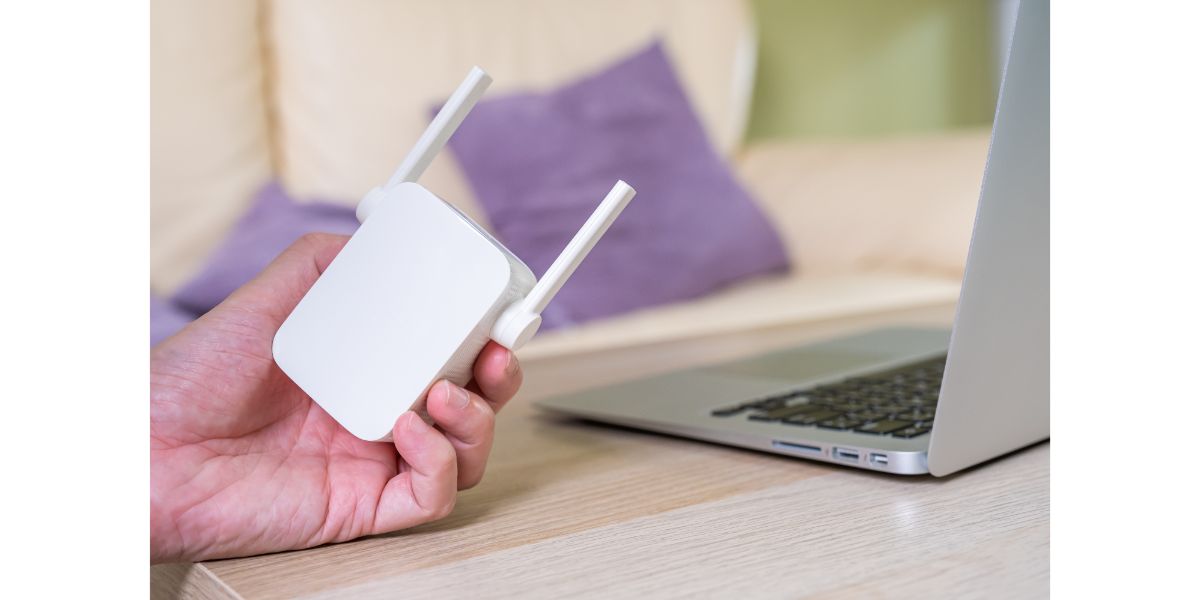 AdobeStock_517361766 wifi extender next to laptop on table in living room