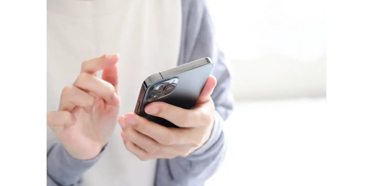AdobeStock_536671666 person trying to text on an iphone 11 with white background