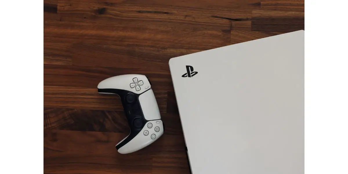 AdobeStock_543232594_Editorial_Use_Only PS5 PlayStation 5 games console with white gaming controller on wood background