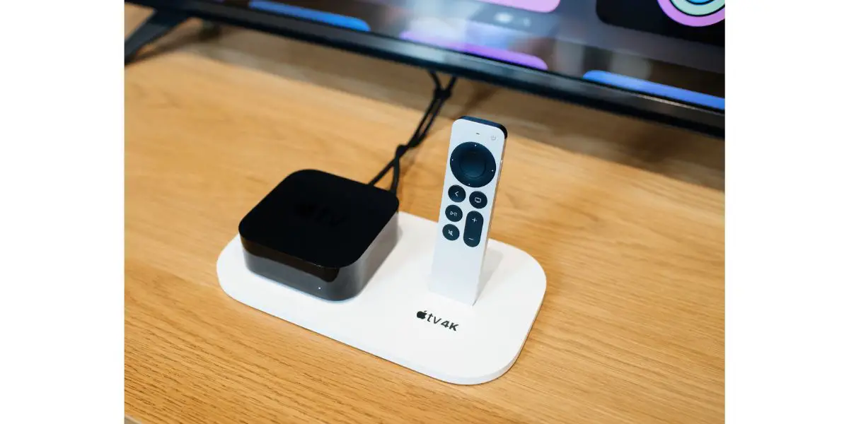 AdobeStock_545782677_Editorial_Use_Only New Apple TV 4K streaming device connected to tv on wooden tv stand next to Siri Remote voice recognition of new touch-enabled clickpad
