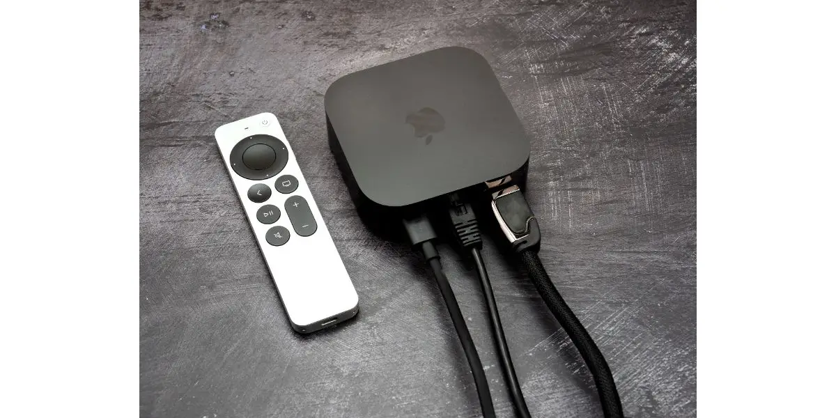 Product shot of the Apple TV 4k 2022 with WiFi and Ethernet, 128Gb RAM, and with Siri Remote, on gray background, back view with cables