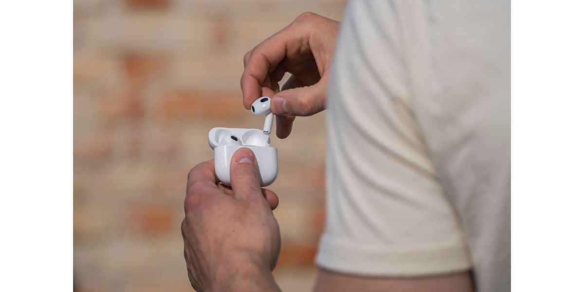 AdobeStock_558101496 hands of a man holding airpods generation 3 on brick background