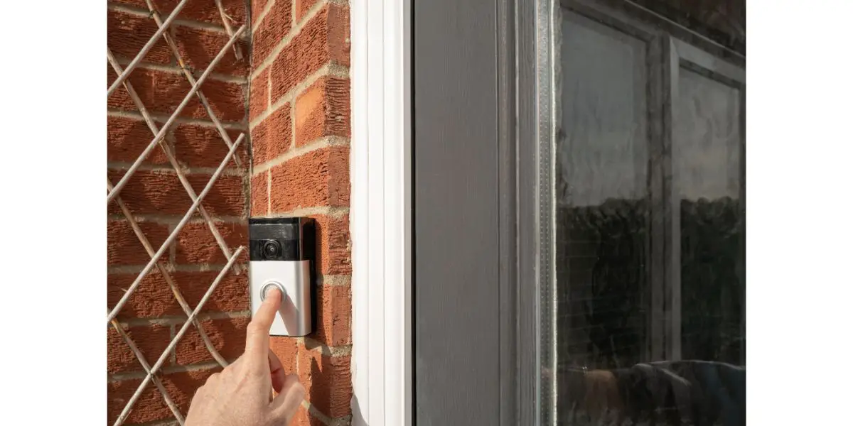 AdobeStock_568506332 Neighbour seen pressing a popular, wireless smart door bell at the front of the house, outside the porch