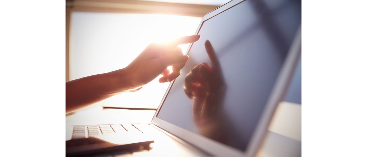 AdobeStock_75699932 Close Up Hand Touching Laptop Screen With sunlight glare