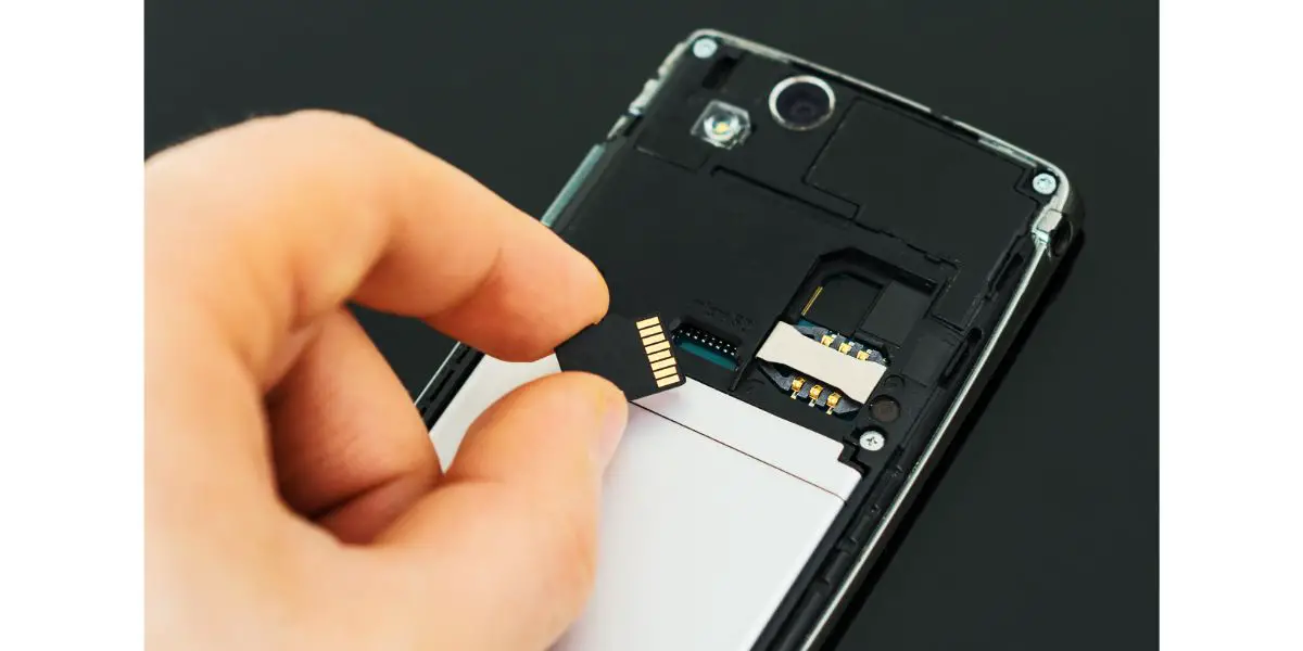 AdobeStock_80622202 Male hand inserting Micro SD card to mobile phone.