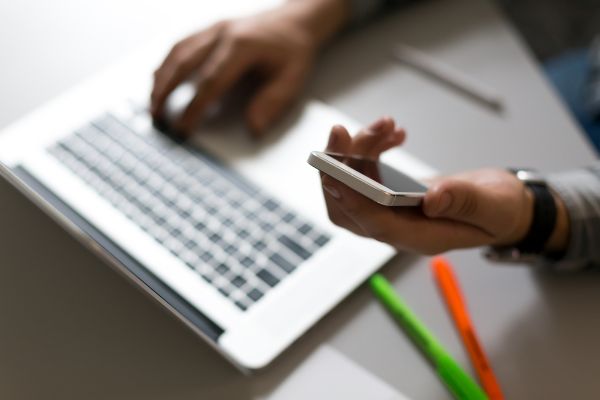 Depositphotos_115094920_S Man holding Telephone in front of Laptop