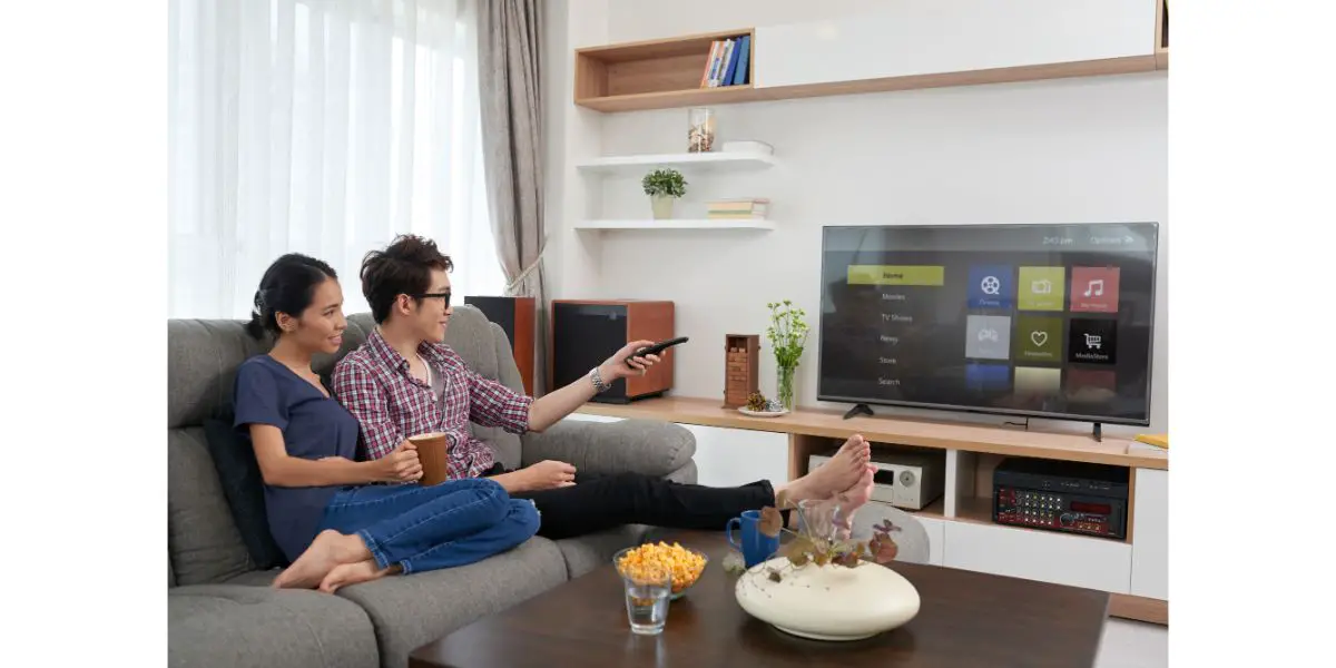 Depositphotos_129221334_L Couple sitting on sofa and watching a smart tv in living room