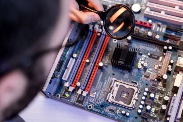 Depositphotos_183961154_S image of man using magnifier while fixing motherboard