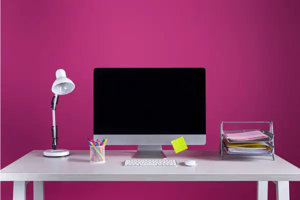 desktop computer with blank screen on pinkish purple backgroun