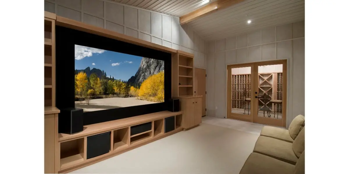 Depositphotos_2107710_L Home theatre with huge smart tv on top of wood tv stands surrounded by shelves in front of a couch